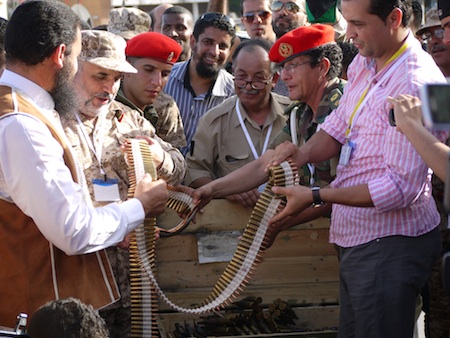 A member of the Zawiya brigade (left) hands in his weapons cache. (Photo: George Grant)