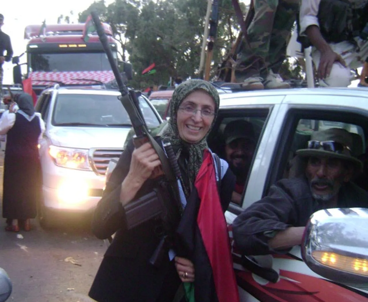 KikhiaAssaultRifle Najat Al-Kikhia poses draped in the Libyan flag and brandishing an assault rifle. (Photo: Maha Ellawati)