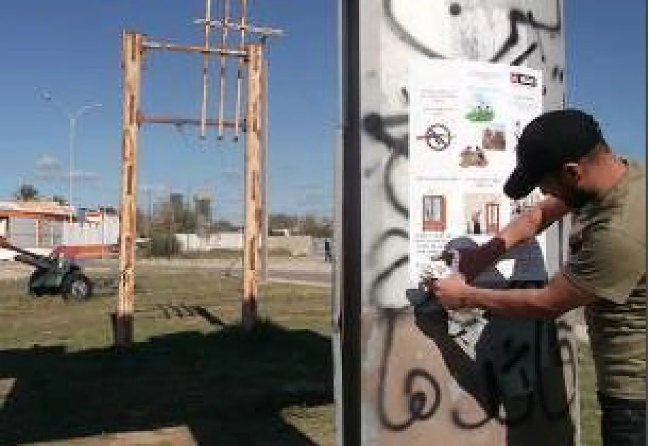 A MAG community liaison officer putting up safety awareness posters in Suq Al-Juma (Photo: MAG)