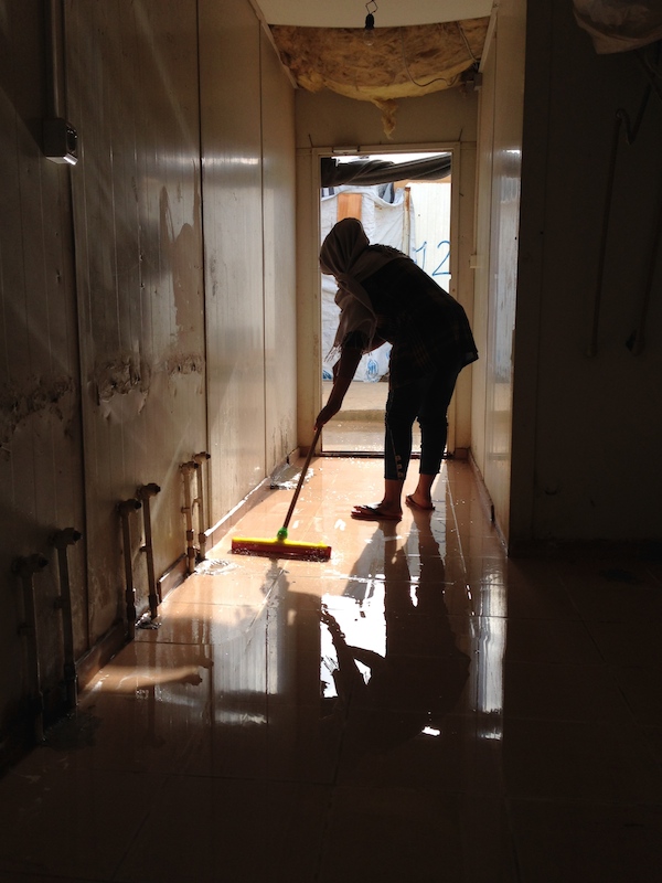 A young woman clears flood waters from a communal area (Photo: Tom Westcott)